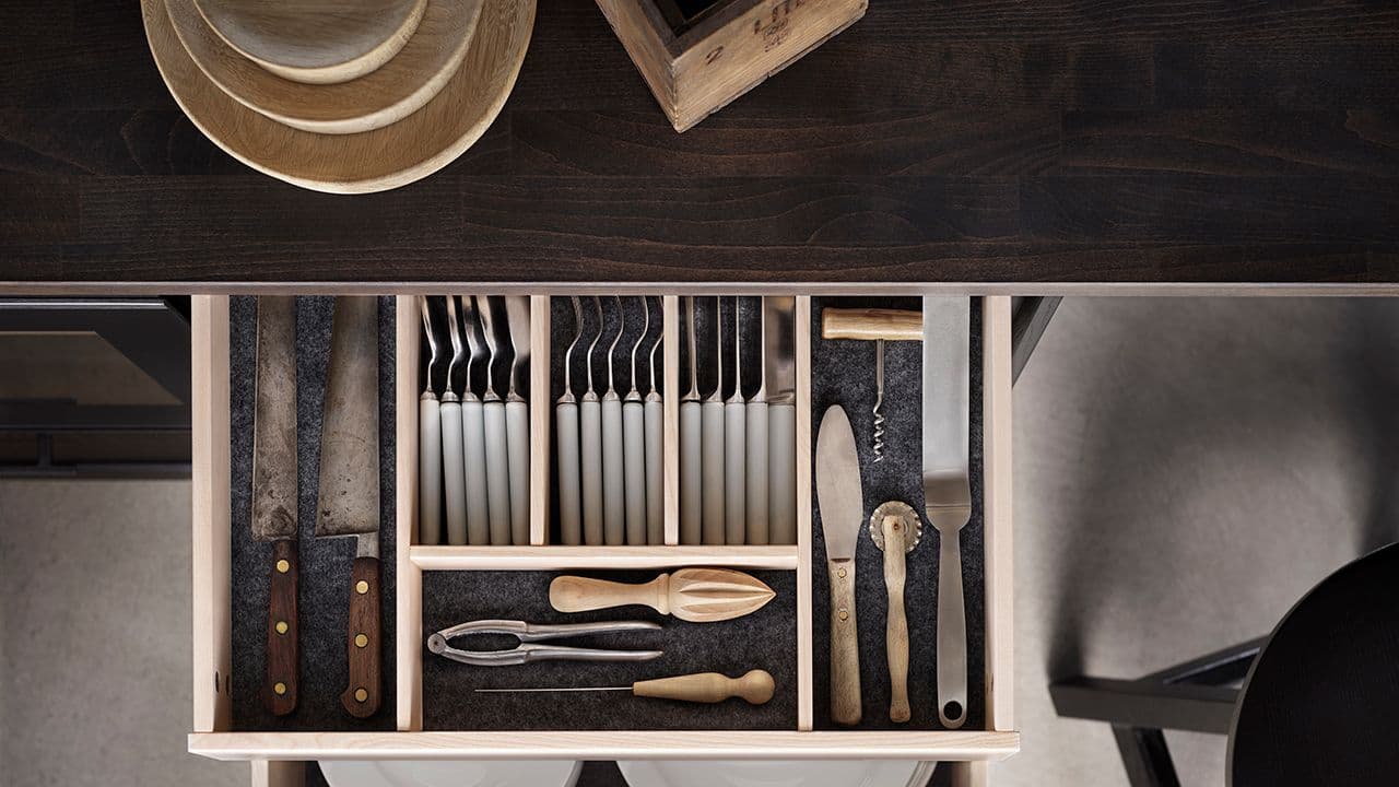 Benkeplate i massivt tre og åpen kjøkkenskuff med kjøkkenredskaper.