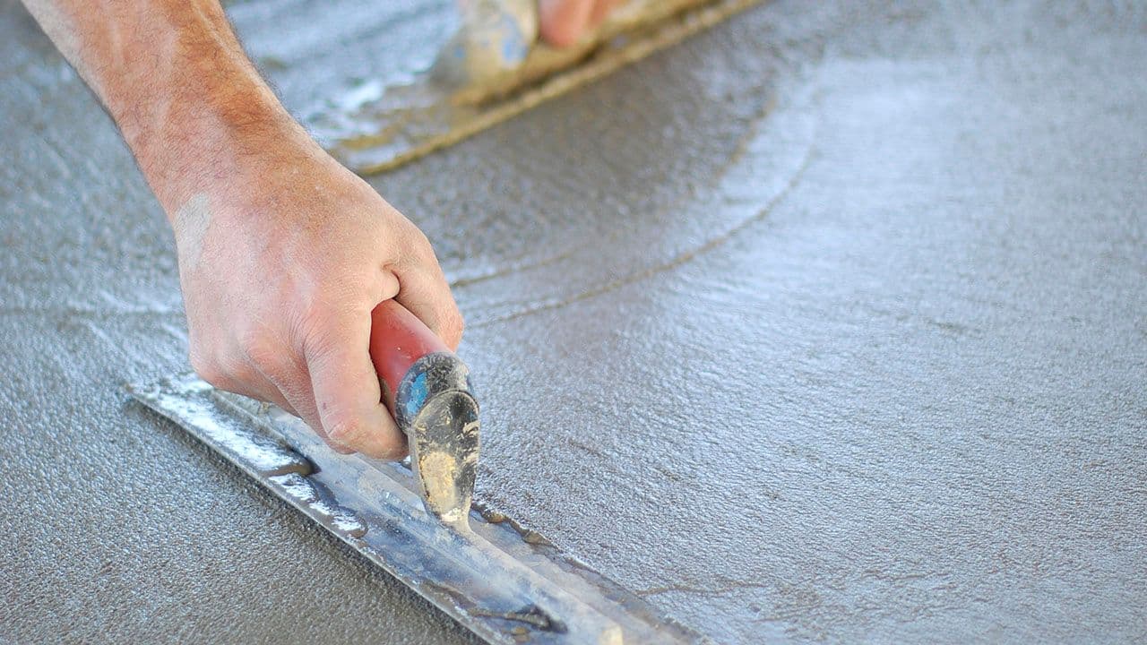 Hånd som støper gulv med sparkelspade.