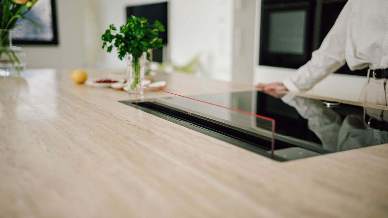 Benkeventilator i glass på kjøkken med lys benkeplate i heltre.