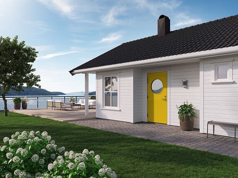 hvitt hus ved sjøen som har knallgul ytterdør med rundt vindu