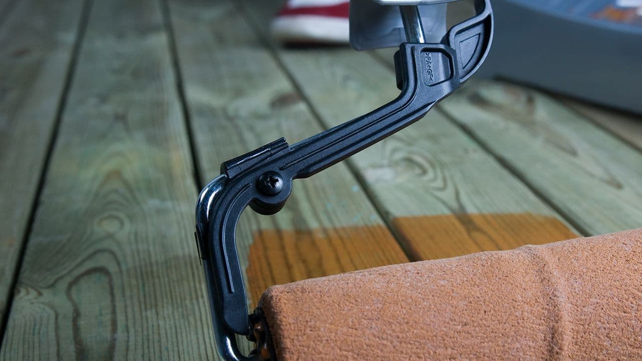 En som holder på å beise terrassen med rulle.