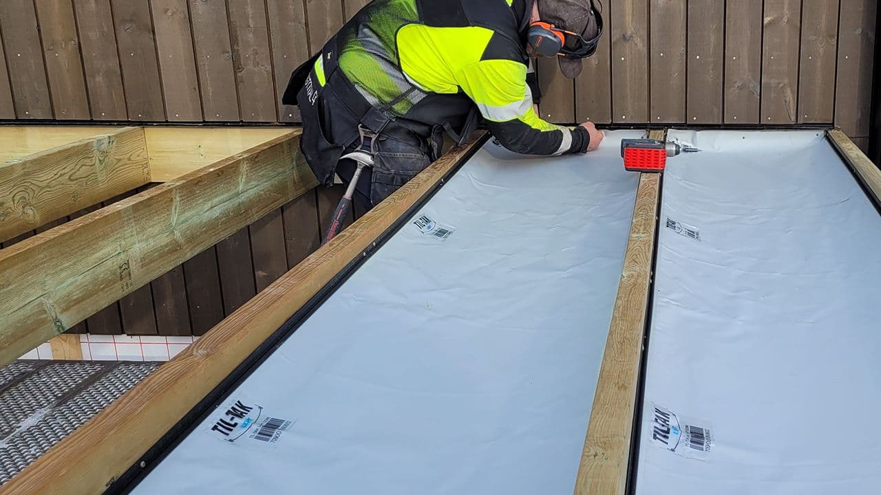 Håndverker som bygger terrasse og fester vanntett duk.