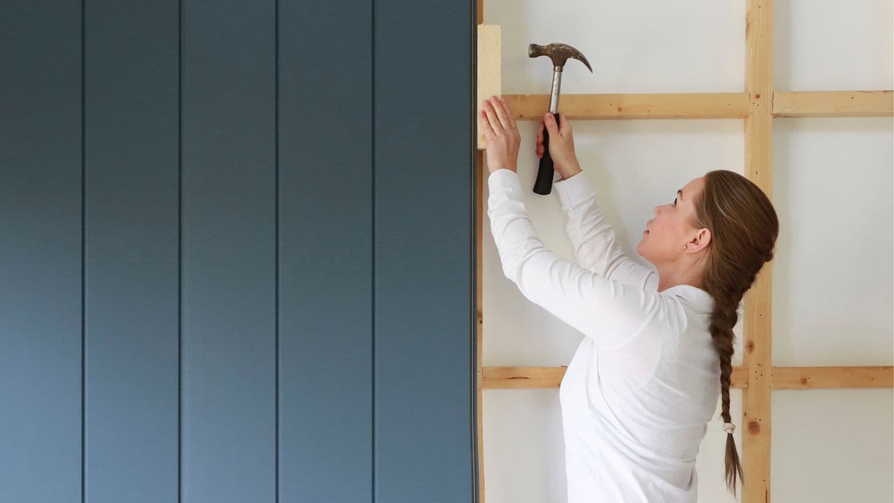 Kvinne som skal montere blå Smartpanel veggplater.