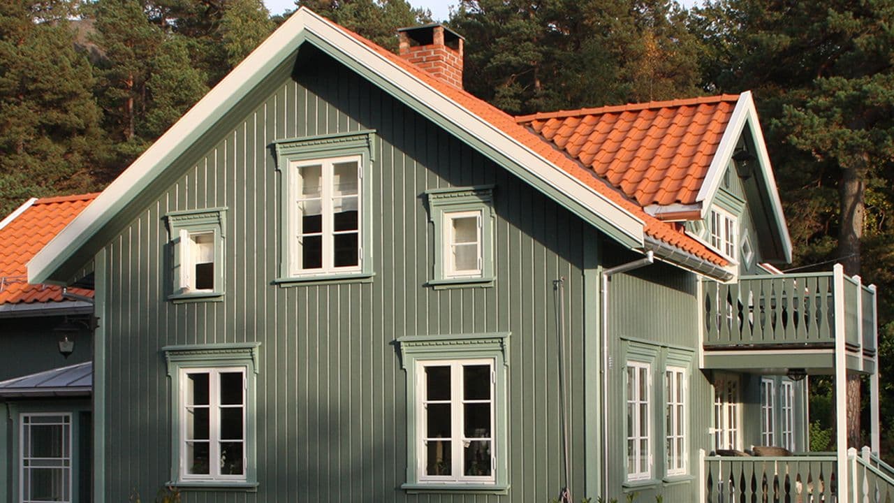 Ny kledning på gammelt hus med takstein og teglsteinspipe.