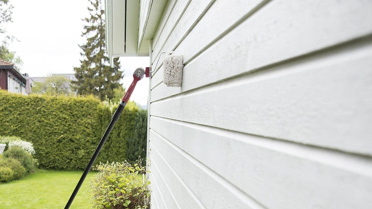Nærbilde av utendørsrulle som brukes til å male hus utvendig.