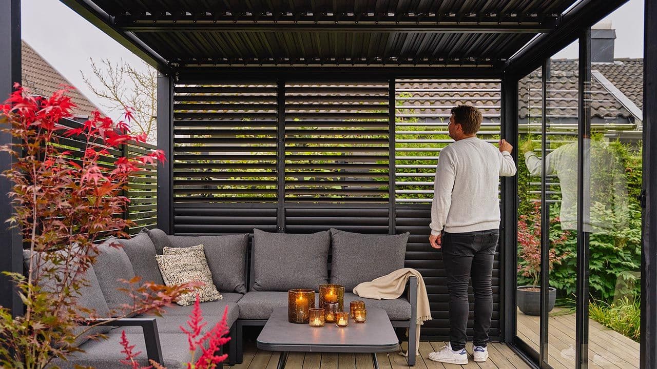 Mann som justerer lamellvegger i pergola.