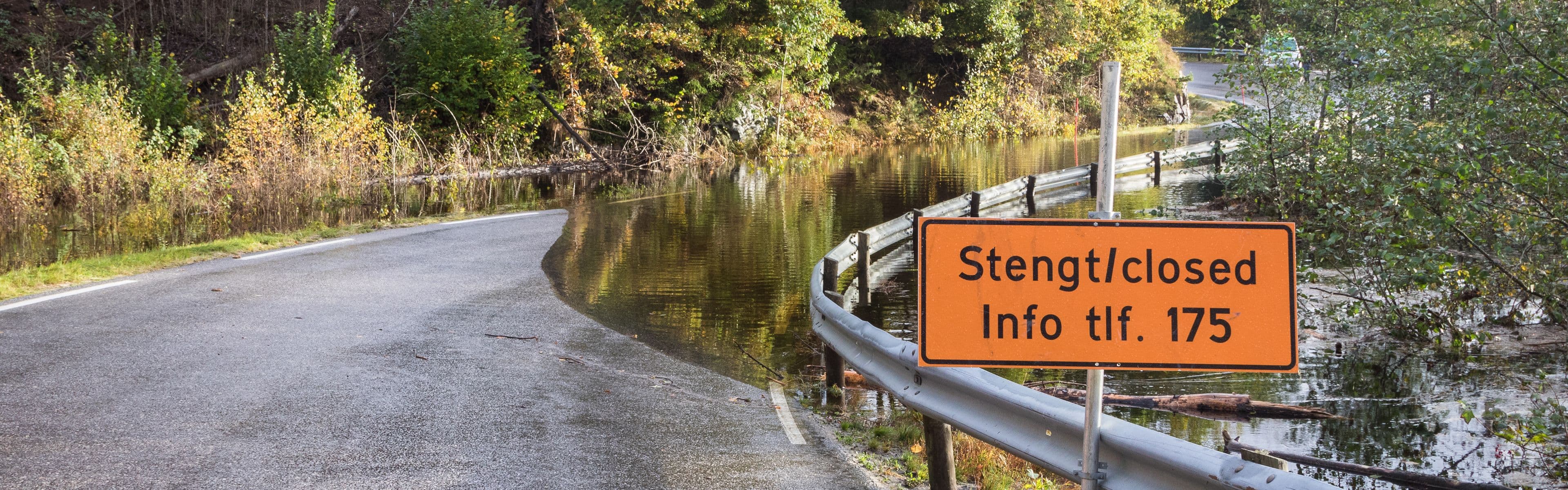 Vei som er oversvømt med vann og stengt på grunn av flom.