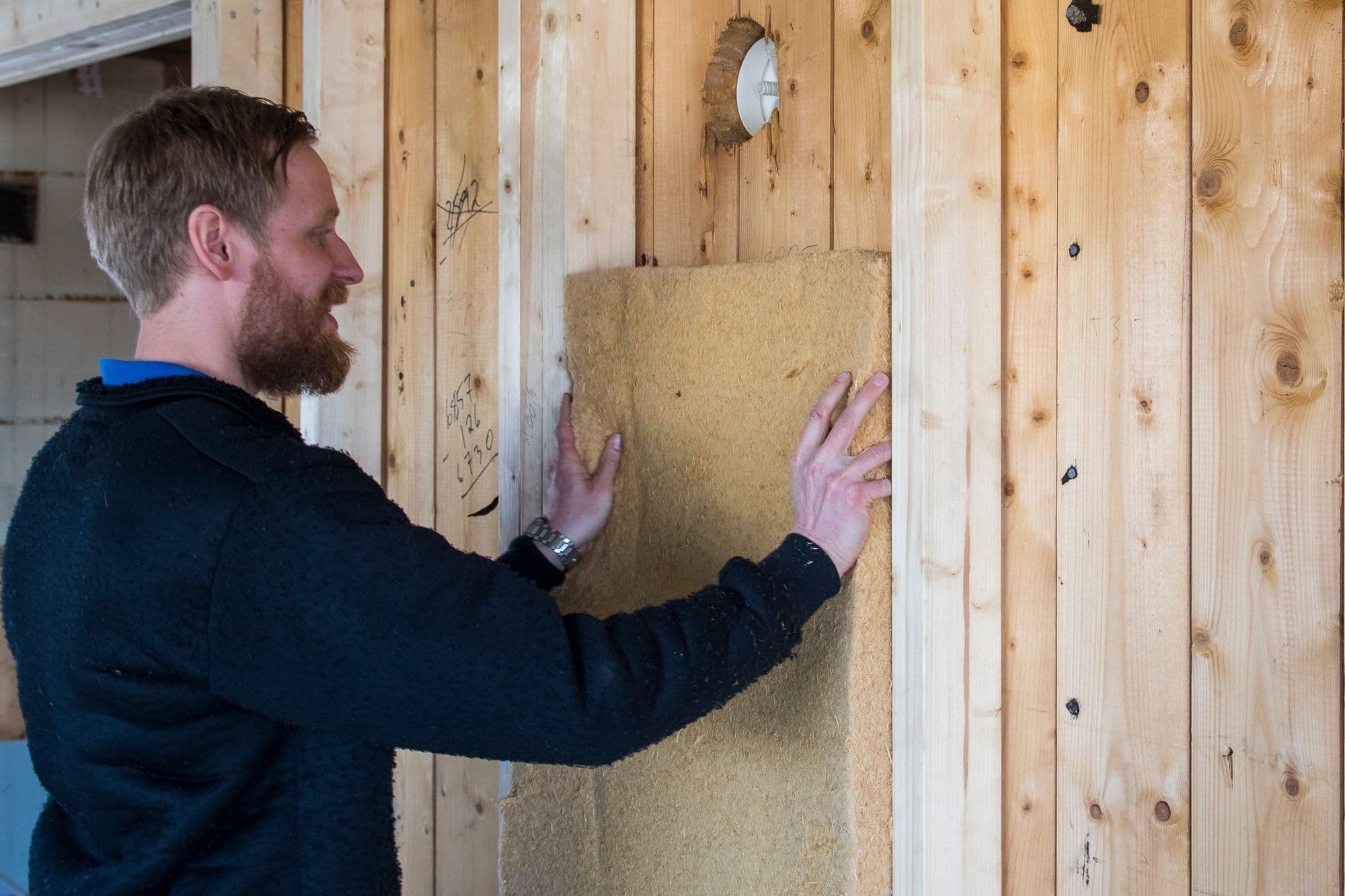 mann isolerer en vegg med trefiberisolasjon