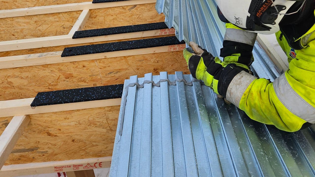 Håndverker som legger svalehaleplater ved brannkrav etasjeskille.