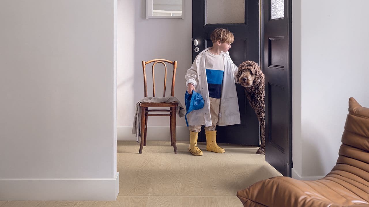 Liten gutt og hund i entré med vinylgulv.