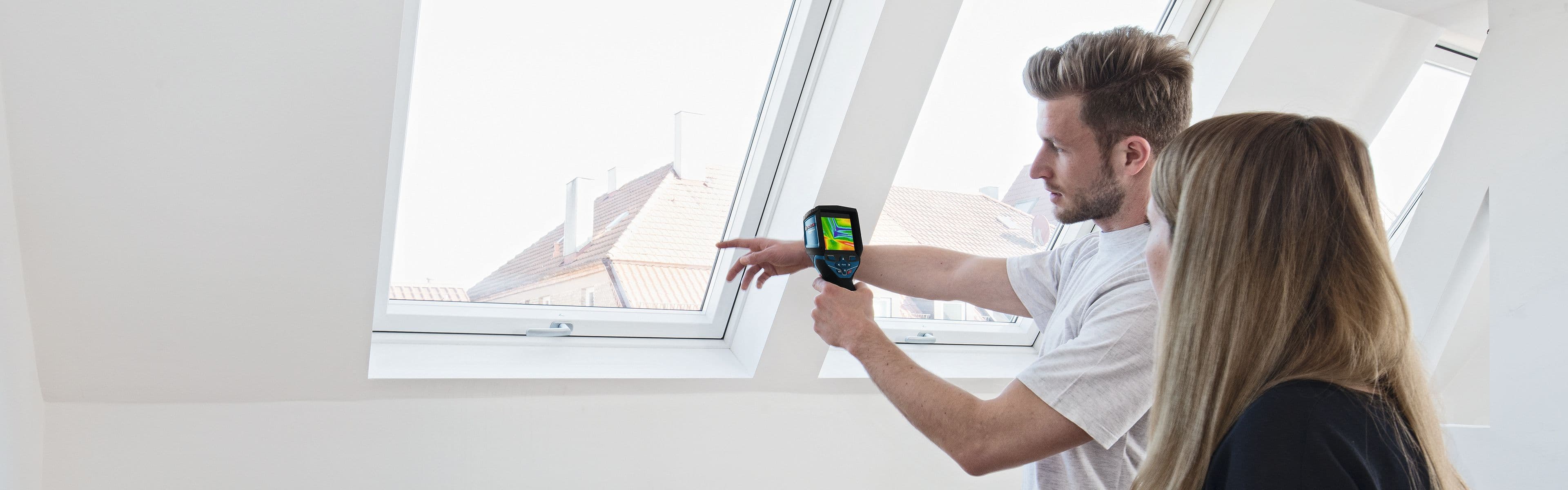 en mann holder Bosch GTC 400 C termisk kamera foran et vindu