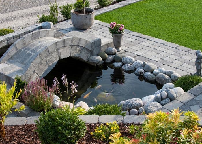 hagedam med beplanting og en liten bro laget av belegningsstein og kantstein