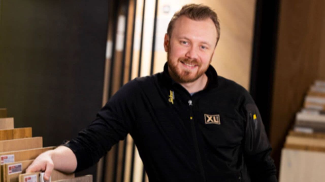 Mannlig XL-BYGG ansatt står ved en gulvutstilling.