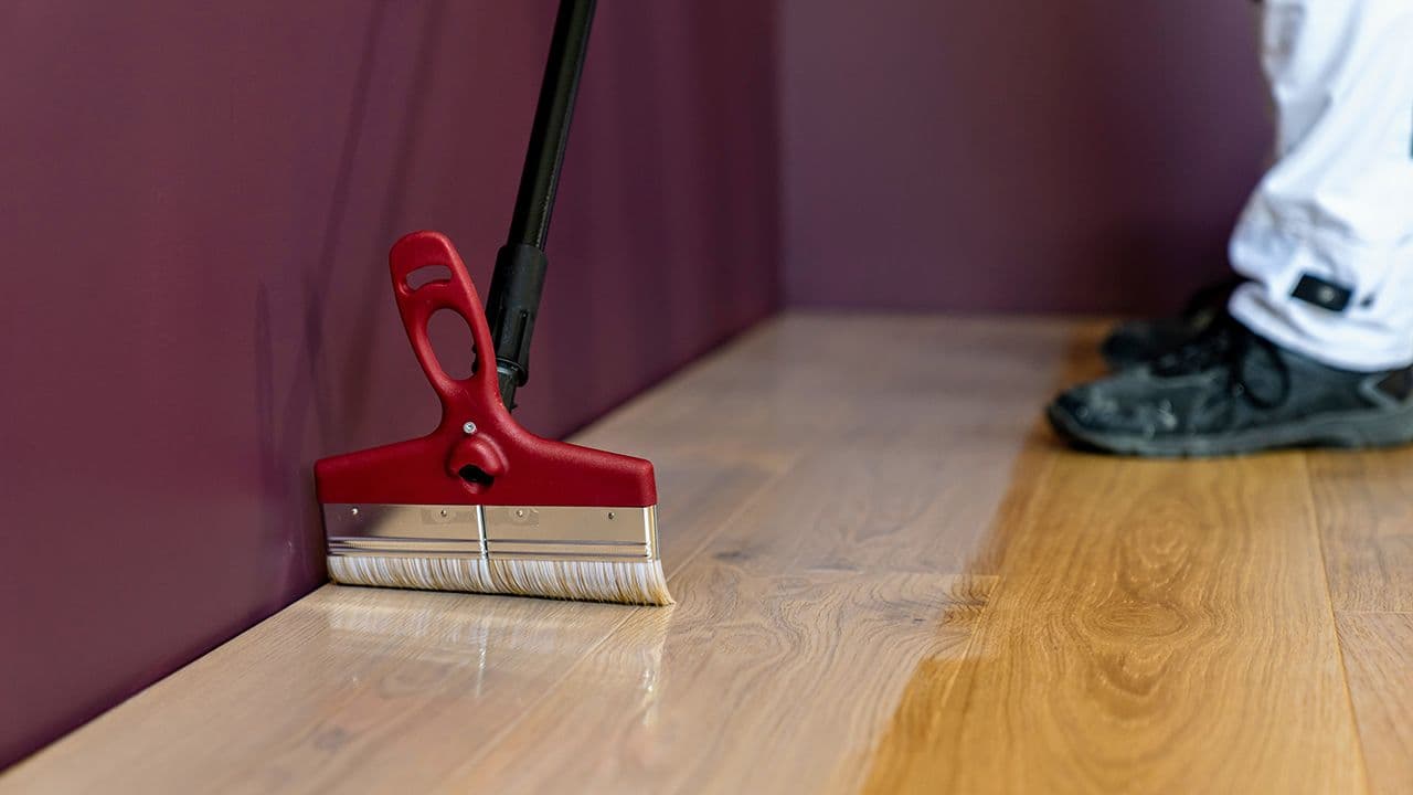 Lakking av gulv med bred pensel.