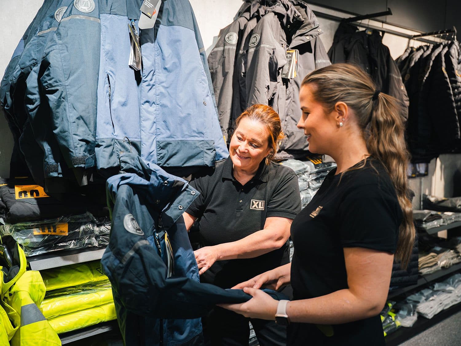 kvinnelige ansatte hos XL-BYGG viser frem arbeidstøy