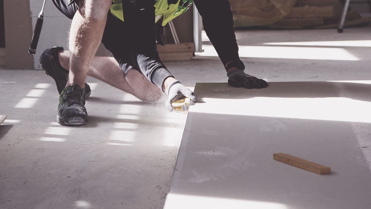 Mann som sliper kantene på veggplate.