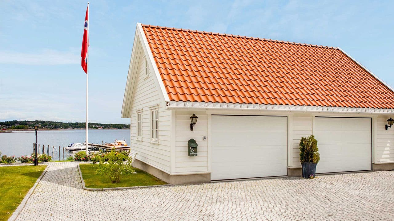 Hvit dobbelgarasje med liggende kledning og dobbel garasjeport.