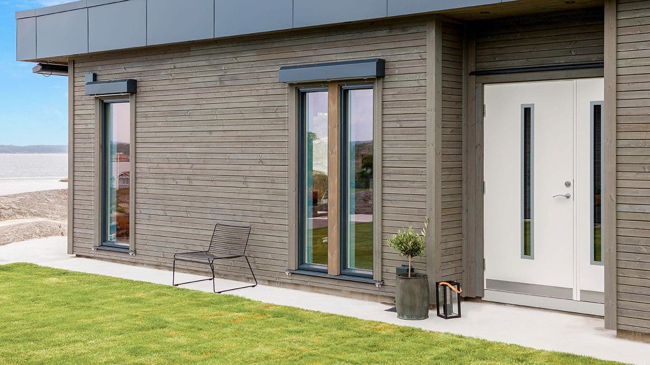 Hvit ytterdør med sidefelt på moderne trehus med flatt tak.