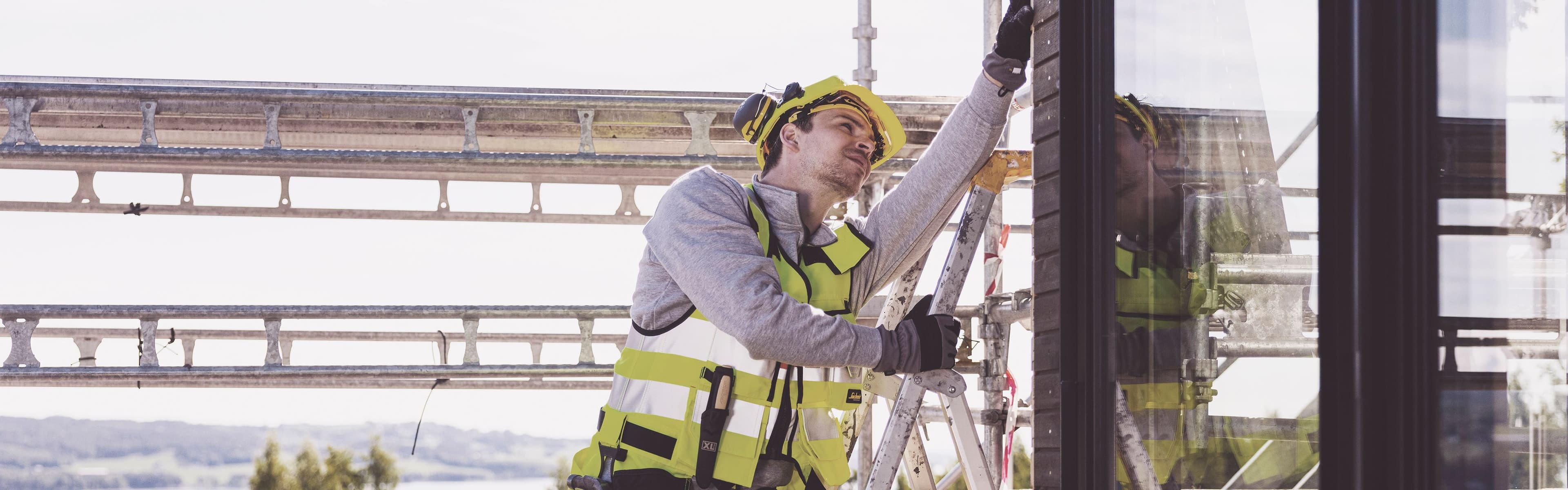 håndverker står i en stige på en byggeplass