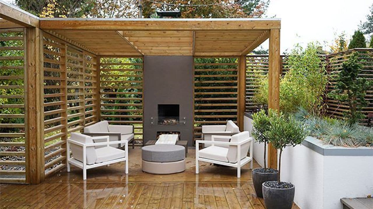 Pergola som gir tak over terrasse med utepeis og sittegruppe.