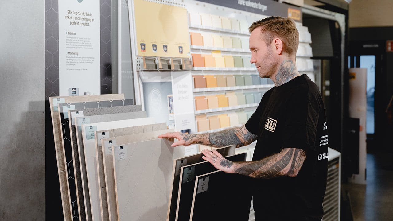 XL-BYGG ansatt som blar i baderomsplater.