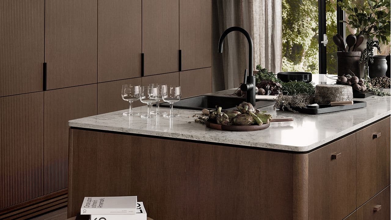 Liten kjøkkenøy i kjøkken med høyskap på bakveggen.