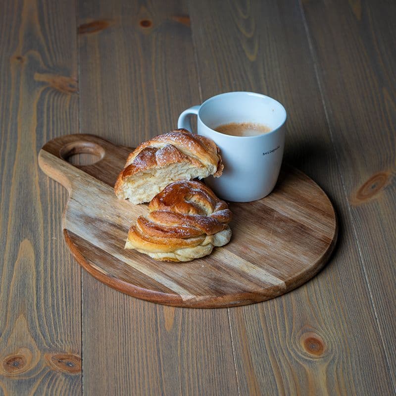 Trefjøl med kanelboller står på et heltregulv i oljet furu