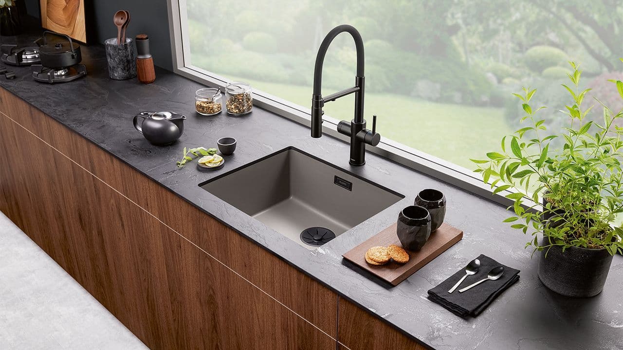 Blandebatteri og vask i sort som går ton-i-ton med benkeplaten.