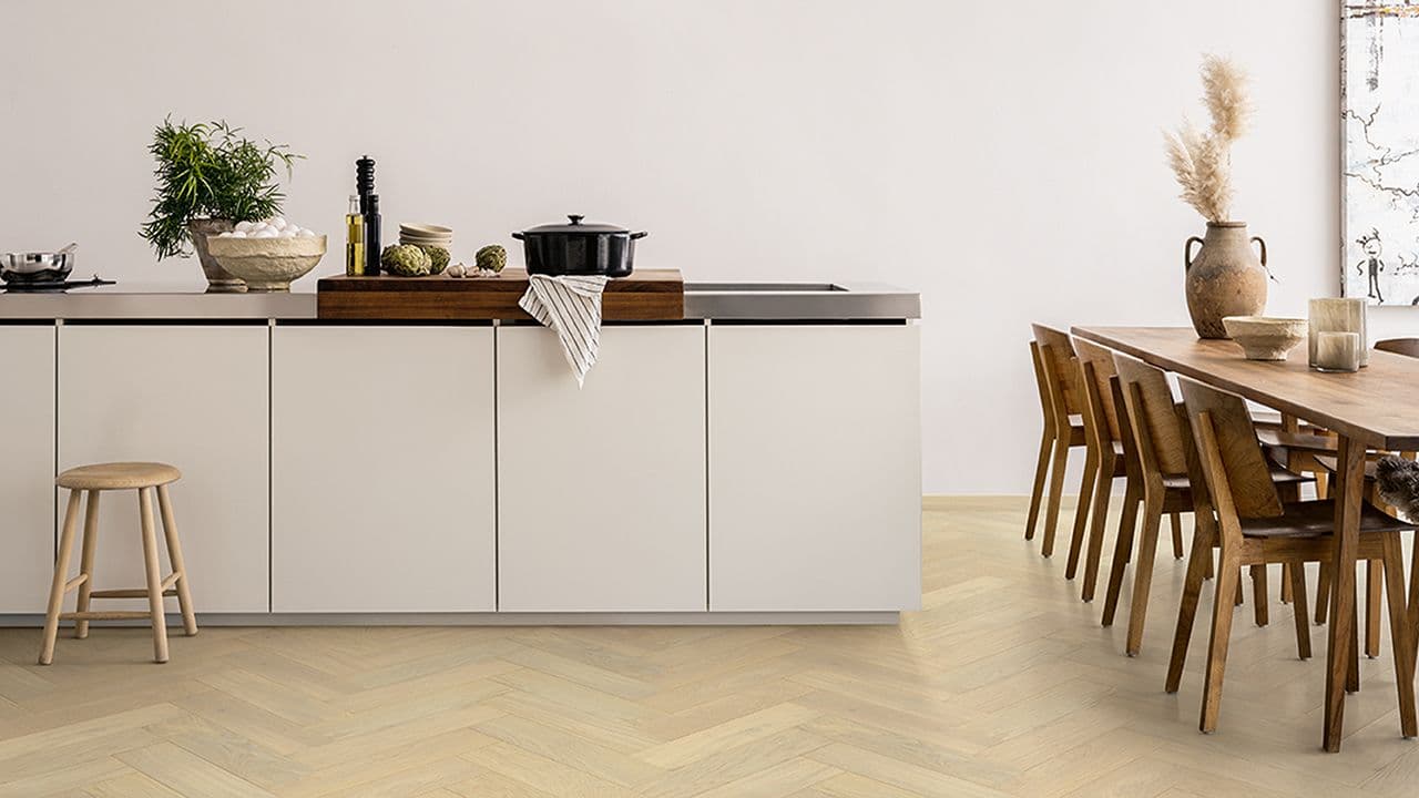 Lyst fiskebeinsgulv på lyst skandinavisk kjøkken.