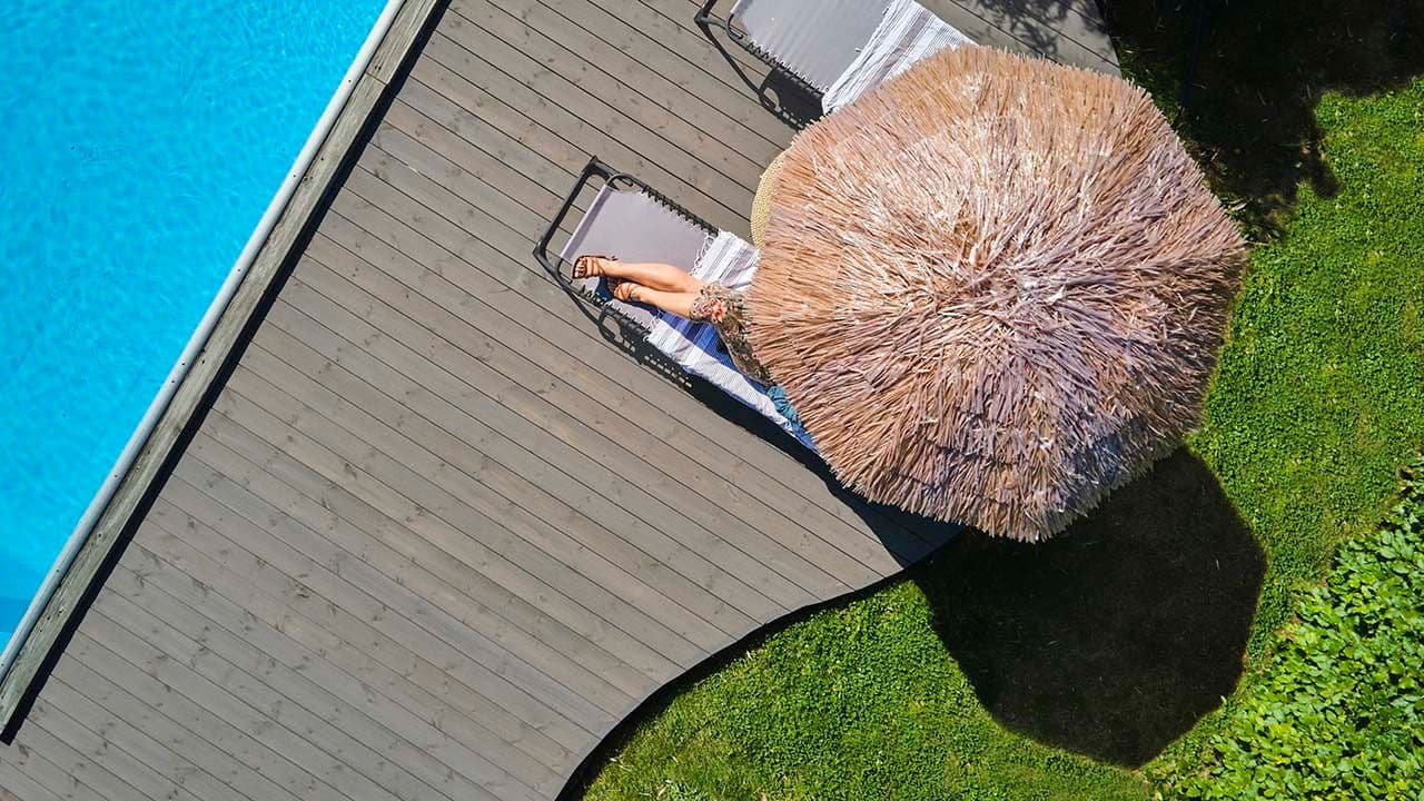 Terrasse med runde former og solstoler i hage med basseong.