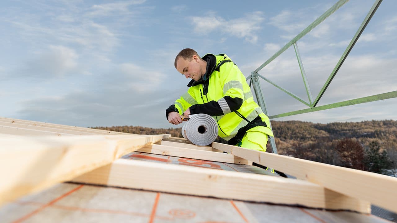 Mann som legger nytt tak for bolig for å tette igjen taket.