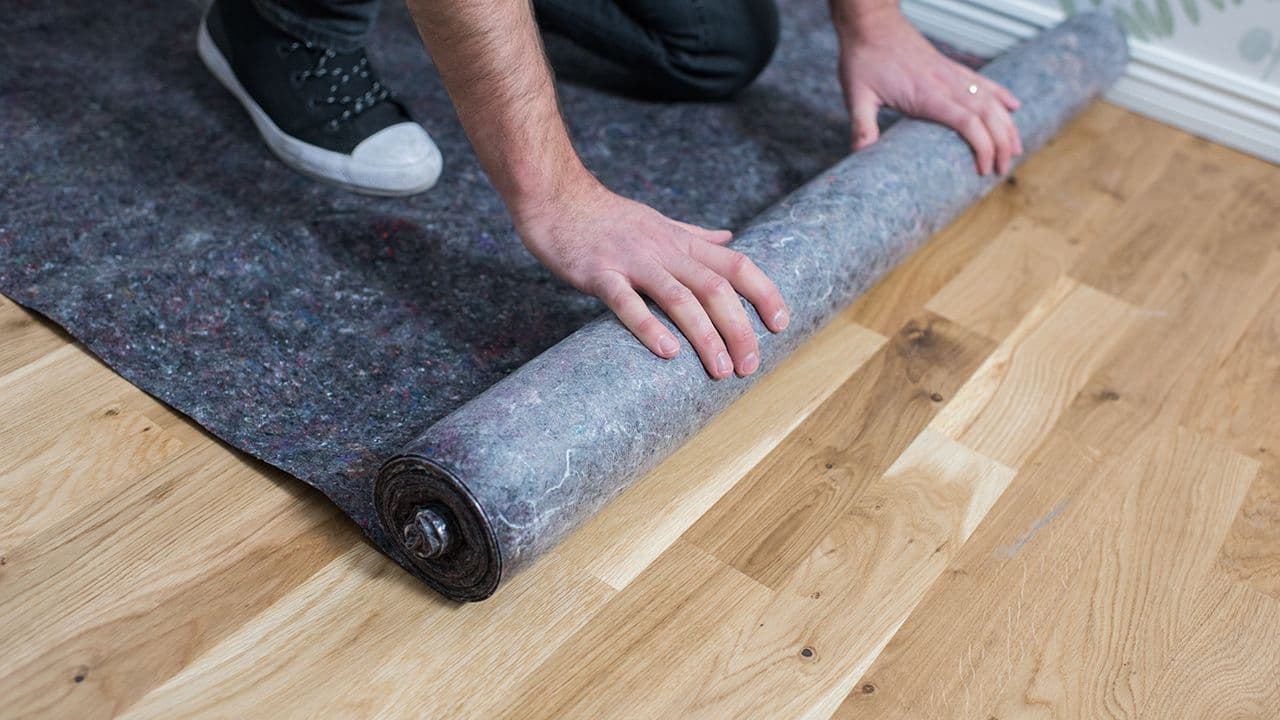 Mann som dekker til gulvet før han skal male vegg inne.