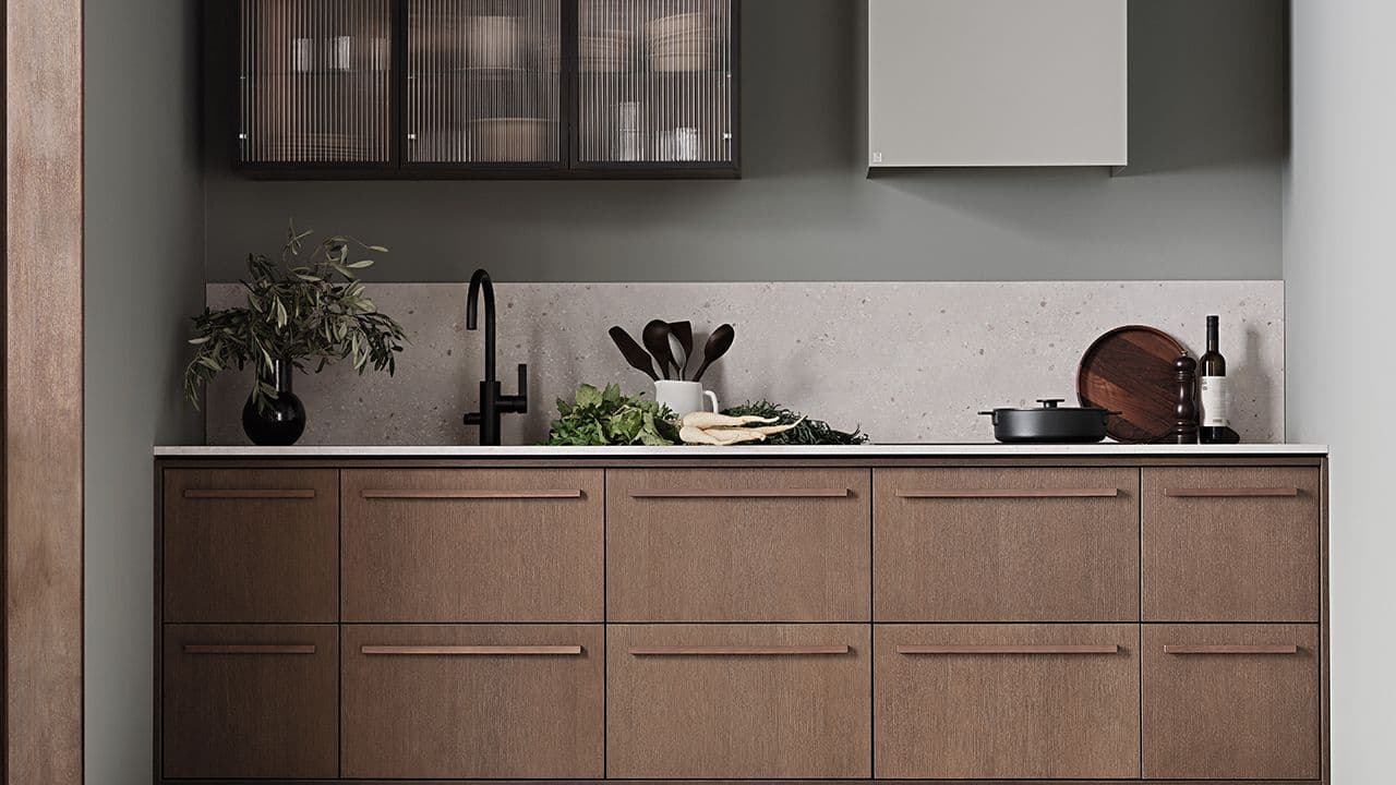 Lite kjøkken i treverk med kjøkkenhette og overskap med glassfronter.