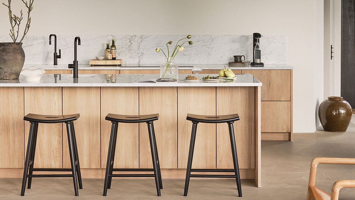 kjøkken i lyst tre med marmor benkeplate som er trukket opp over veggen som sprutbeskyttelse