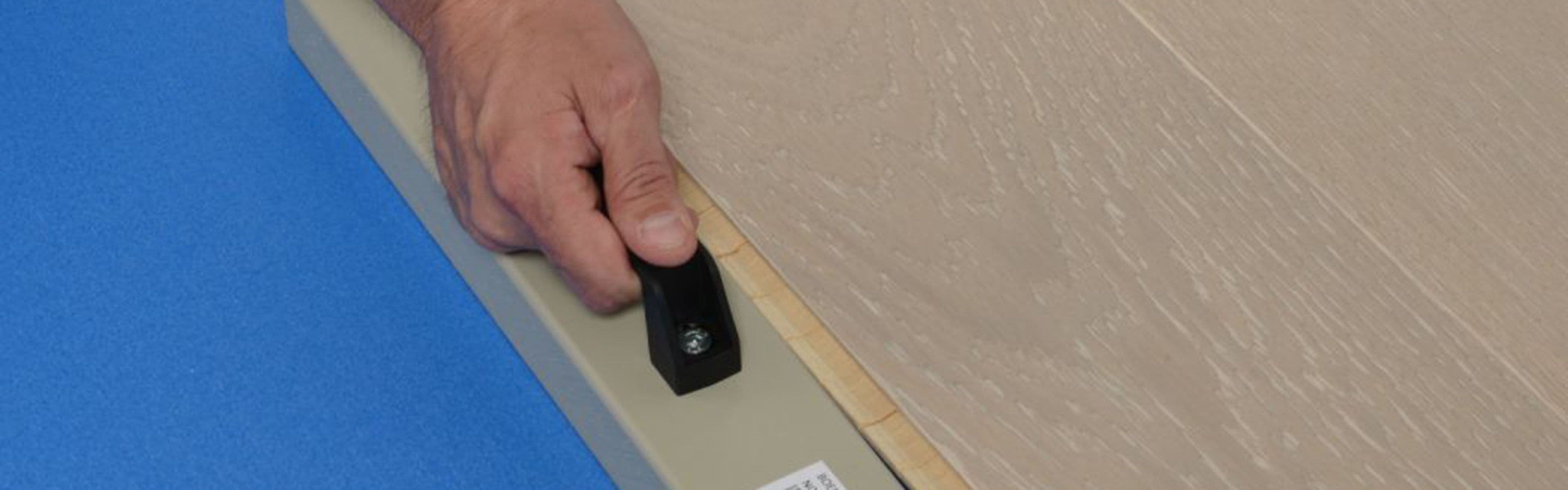 Hånd med slagkloss som legger gulvunderlag under parkett.