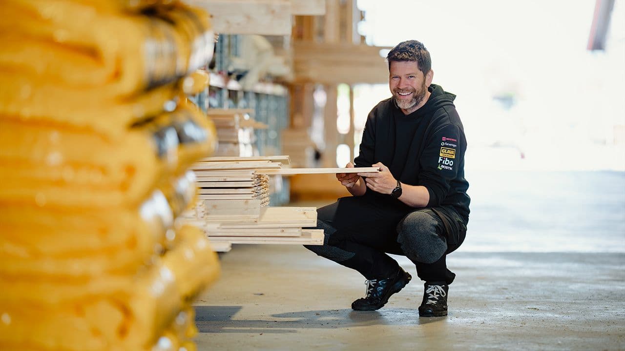 Xl-Bygg ansatt som sitter på huk og holder byggeplater på et lager.