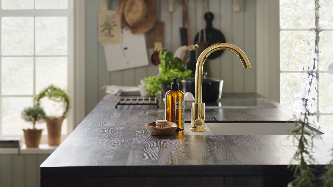 Benkeplate i svart heltre på lysegrønt kjøkken.