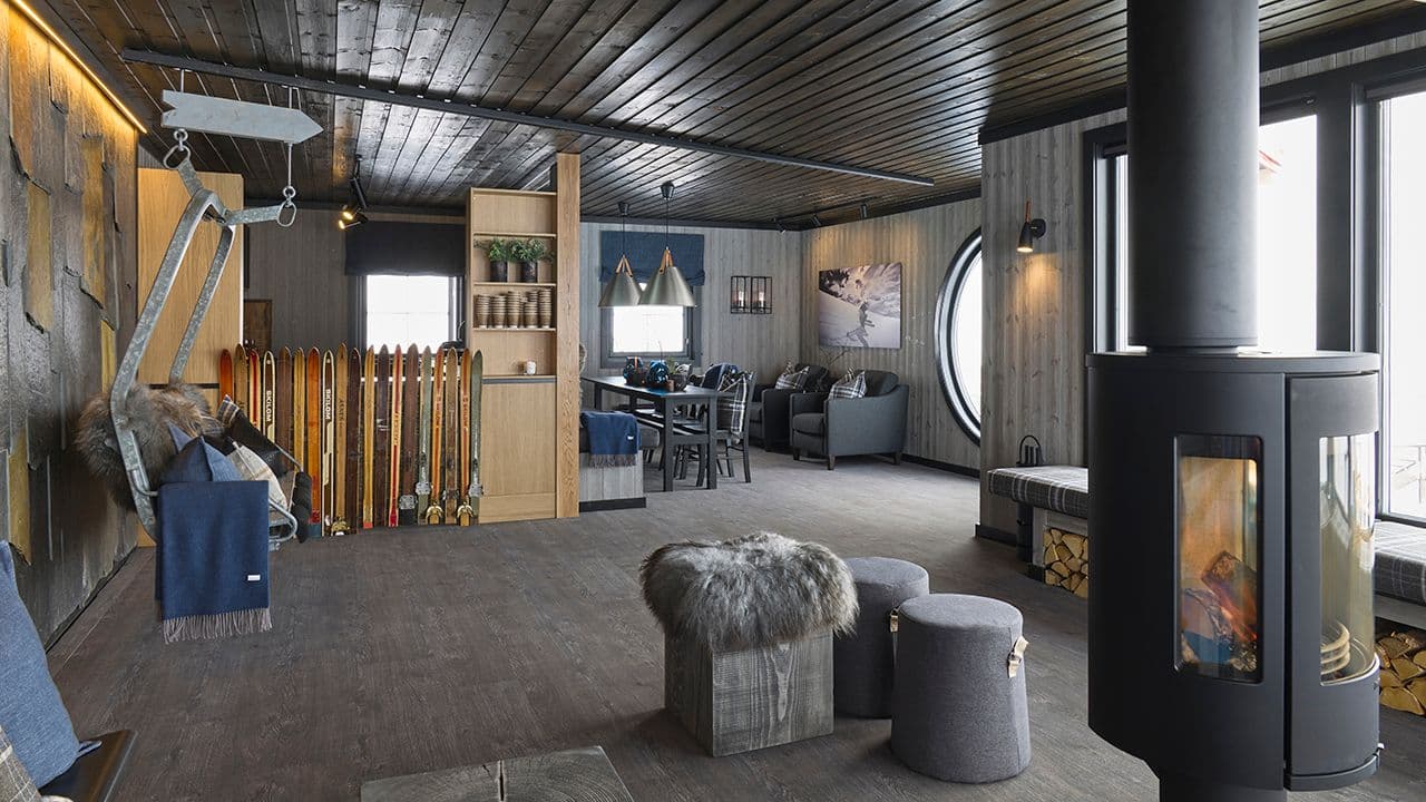 Gammel hytte som er pusset opp med mørke panelvegger og tak.