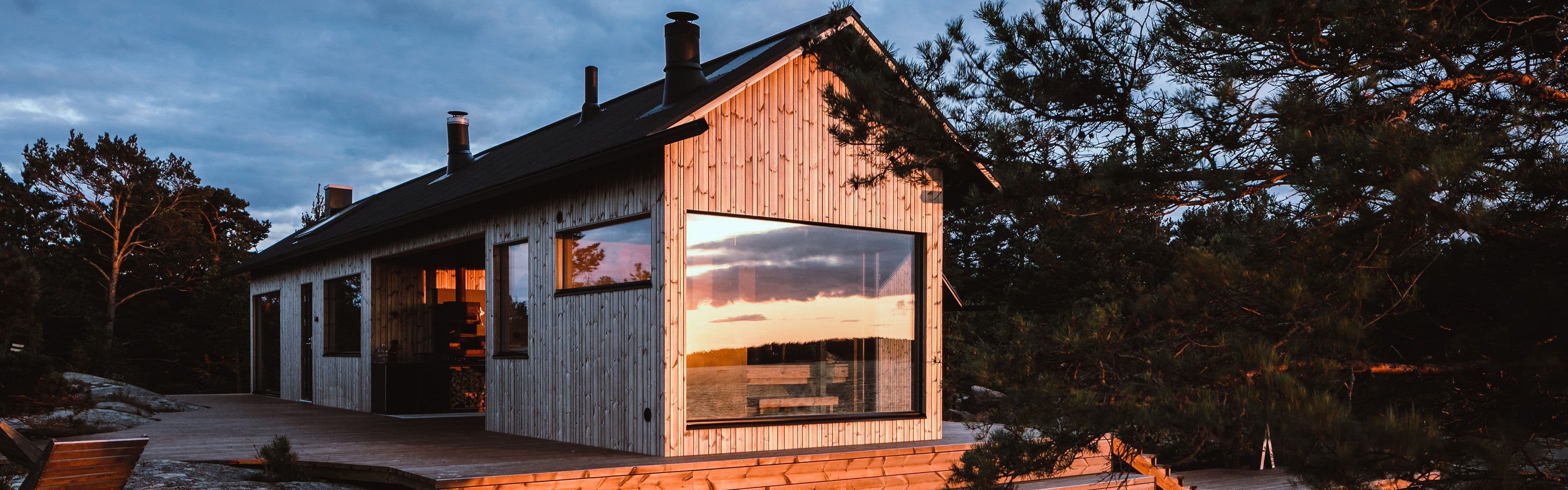 Moderne hytte med kledning i solnedgang.