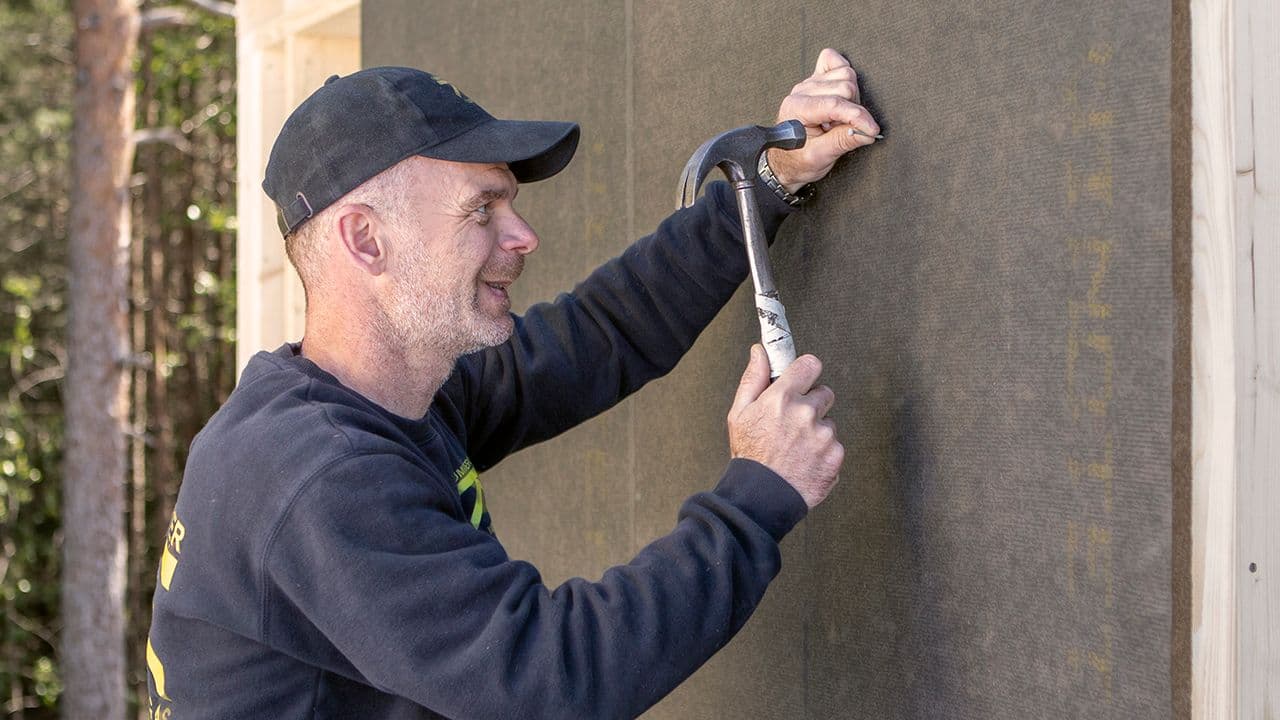 Mann som spikrer på plass vindsperre.