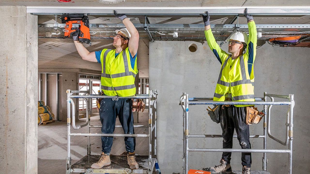 To håndverkere som monterer med Spit Pulsa P65 boltepistol som gir nesten null støv ved bruk.