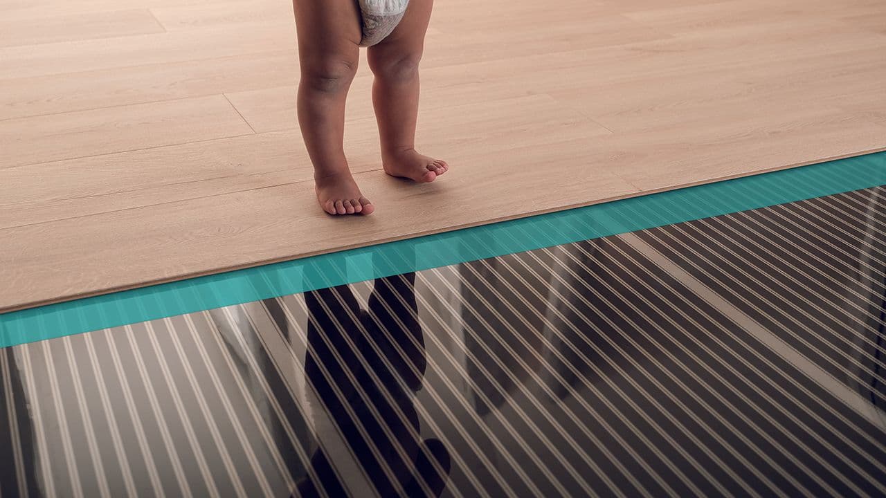 Barneføtter som står ved skille mellom parkettgulv og varmekabler.