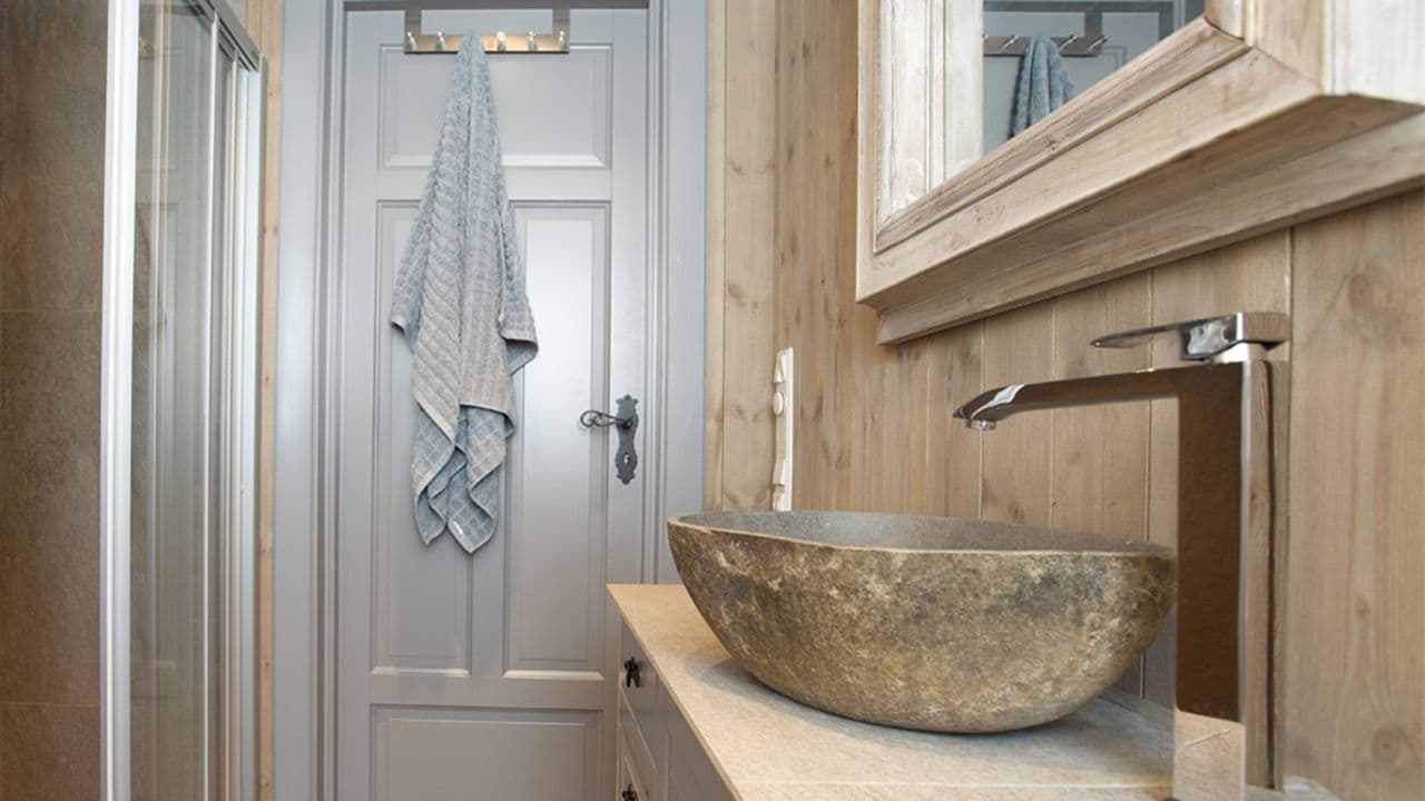 Lyst trepanel på hyttebad med detaljer i krom.